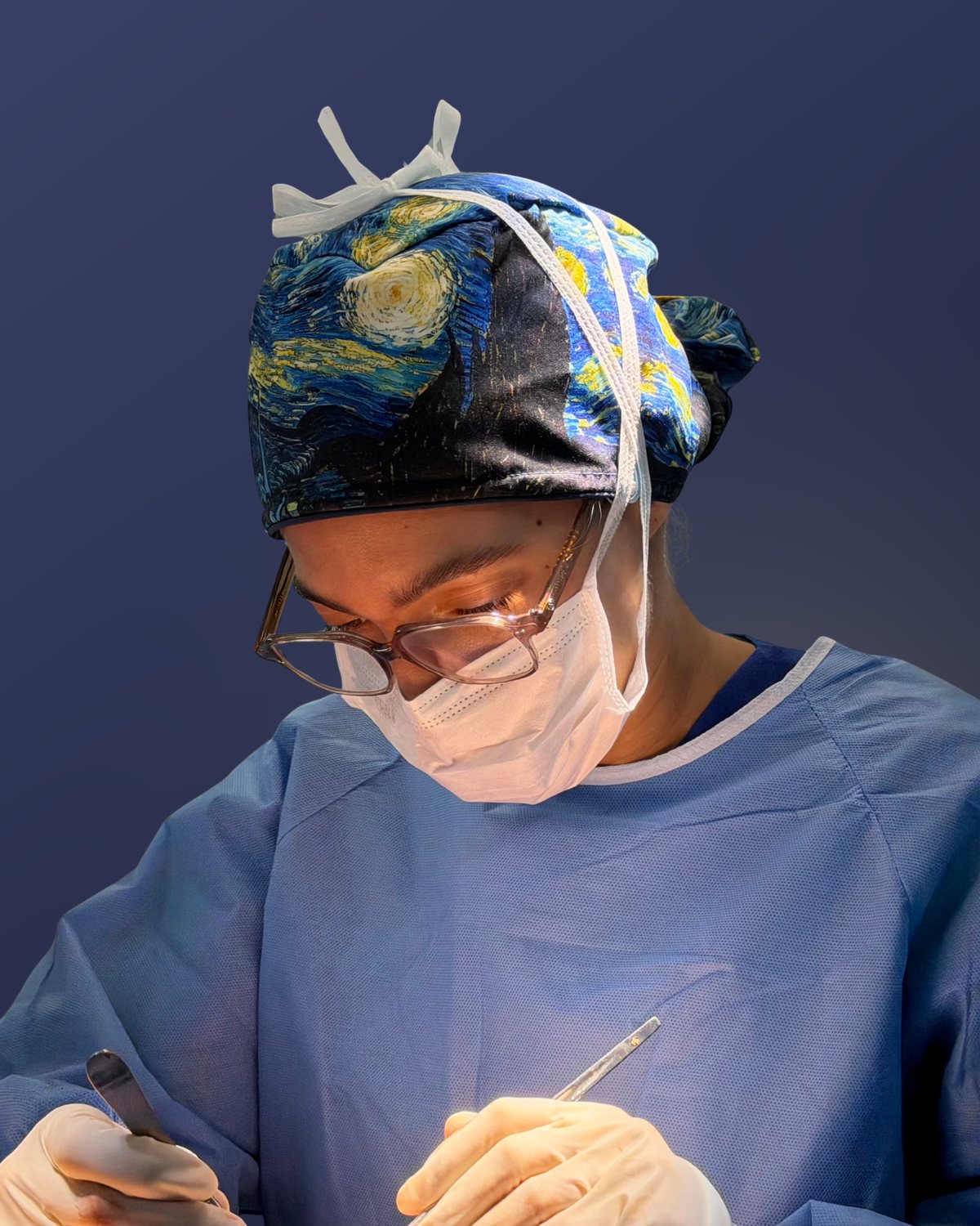 La Dra. Génesis Cruz Viñas operando, con gorro quirúrgico estampado, lentes de protección y mascarilla.